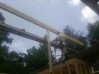 Carpenter setting a ridge beam over a new addition frame — Ice Dam Removal by Roofing Brothers in Plum Branch