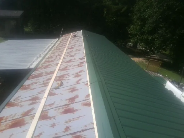 Old rusted panels beside newly installed green metal roofing — Wind Damage Roof Repair by Roofing Brothers in Plum Branch