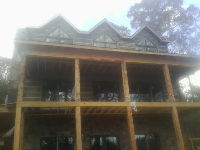 Dormers and porch framing on a large log home under construction — Roof Coating work by our crew in Plum Branch