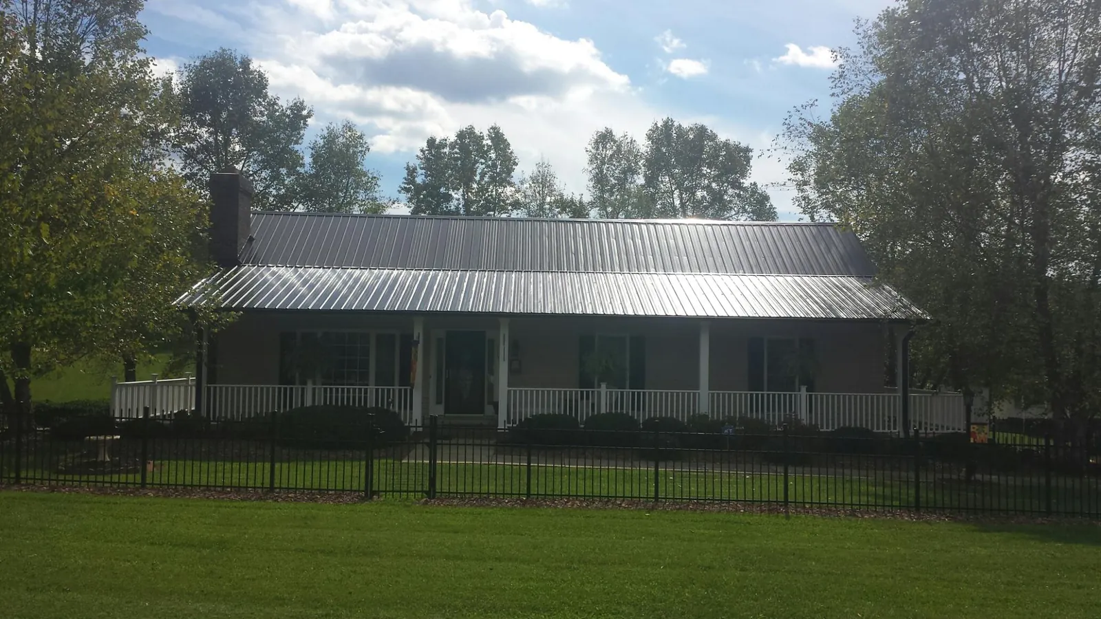 Gray metal roof on a brick ranch with a full width front porch — Gutter Guard Installation work by our crew in Plum Branch