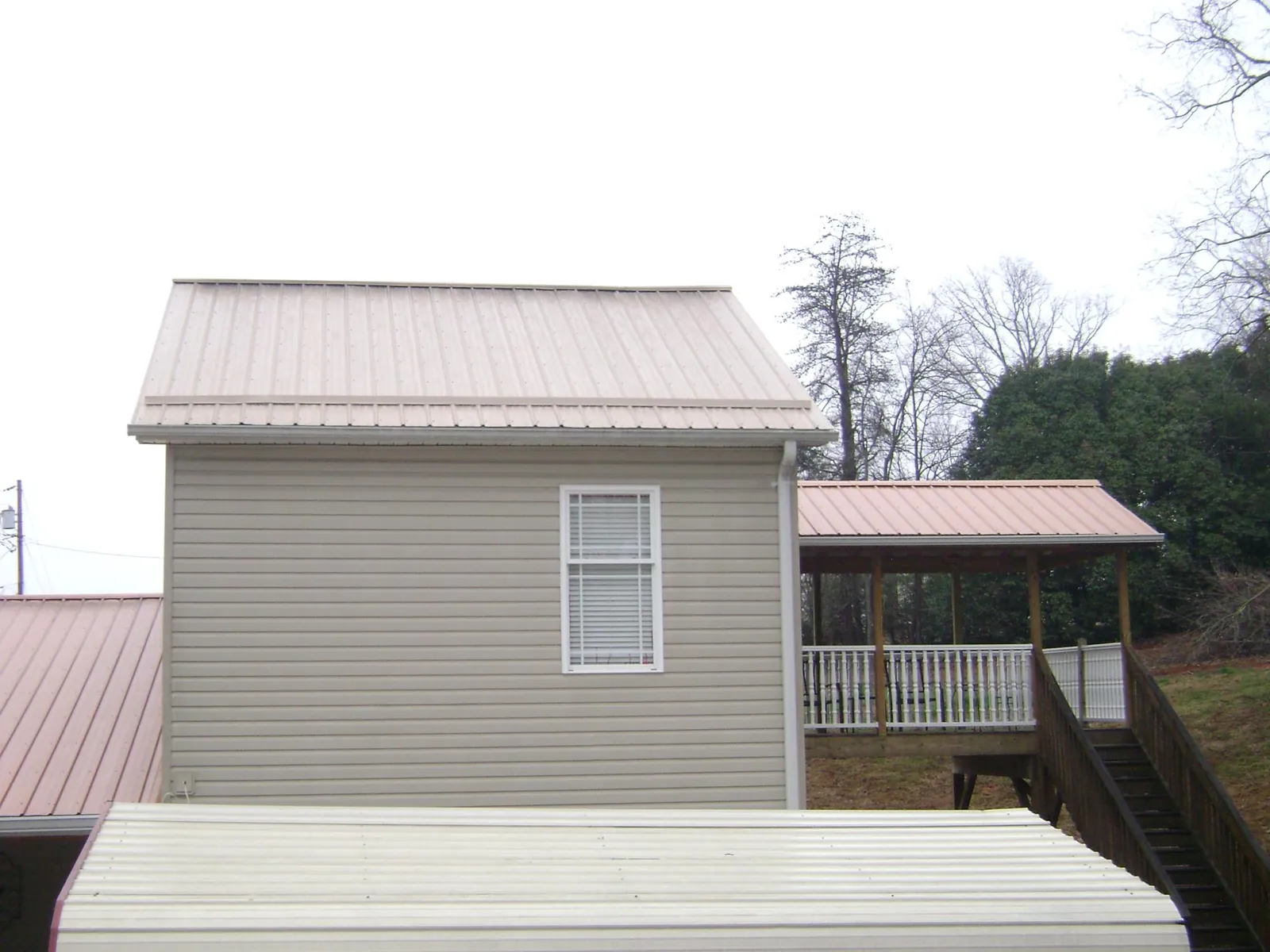 Tan metal roofs on a two story addition and attached porch in Plum Branch