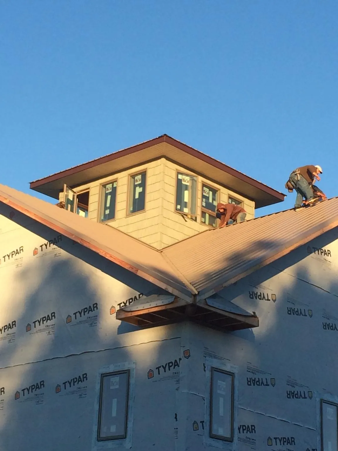 Roofers working around a rooftop cupola on a new metal roof at sunset — Roof Waterproofing in Plum Branch by Roofing Brothers